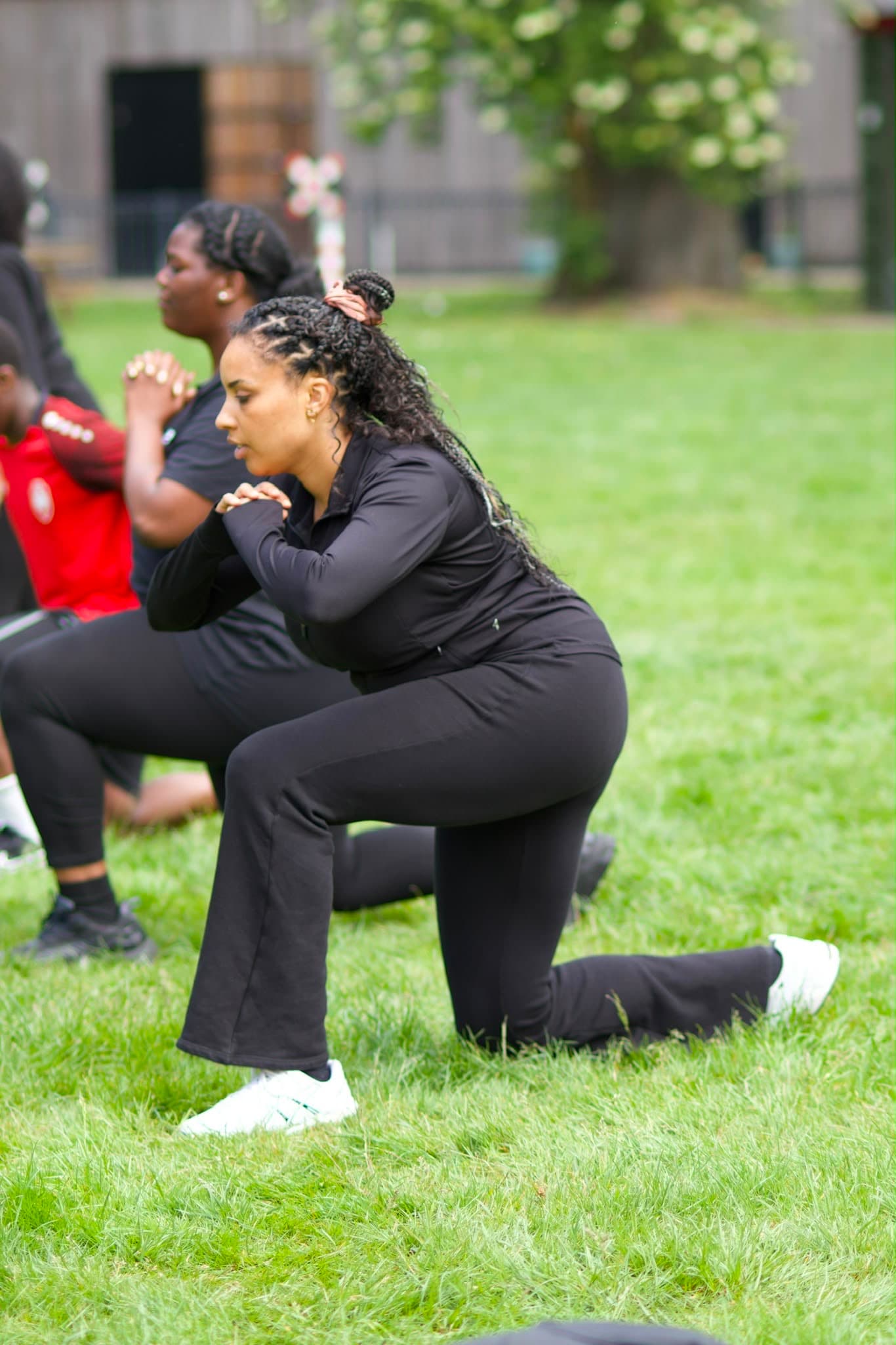 Deelnemers doen samen lunges tijdens de buitentraining in het park.